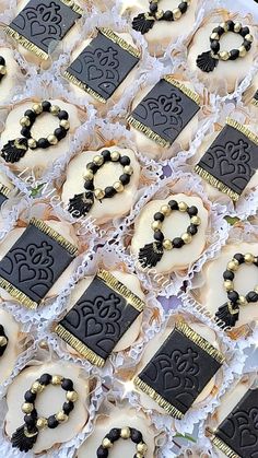 many decorated cookies are on display in a box with black and gold trimmings