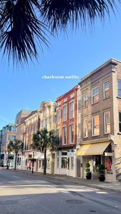 a row of buildings on the corner of a street with palm trees in front of them