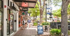 people walking down the sidewalk in front of an ice cream shop on a sunny day