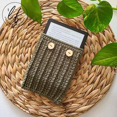 a cell phone case sitting on top of a wicker basket next to green leaves