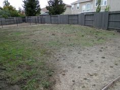 an empty backyard with no grass in the middle and fenced in area behind it