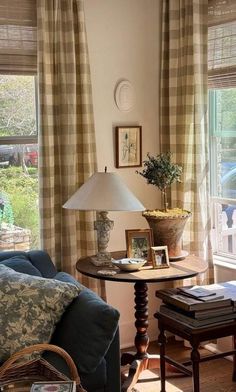 a living room filled with furniture and a lamp on top of a wooden table next to a window