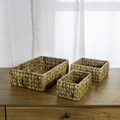 three woven baskets sitting on top of a wooden table