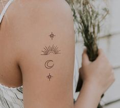 the back of a woman's shoulder with sun and moon tattoos on her left arm