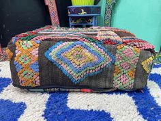 a multicolored bag sitting on top of a blue and white rug next to a mirror