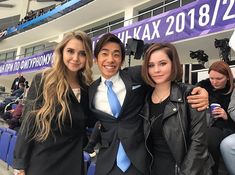 two women and a man posing for a photo in front of an audience at a sporting event