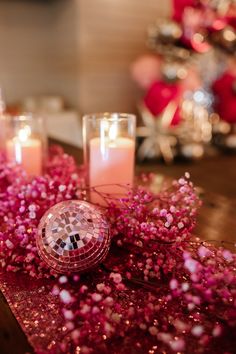 some candles are sitting on a table with pink flowers and other decorations in the background