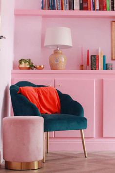 a living room with pink walls and shelves filled with books, furniture, and decor