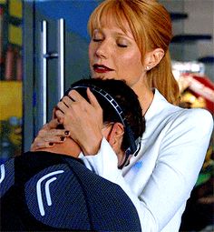 a woman is hugging a man with his arm around her head in front of a refrigerator