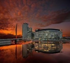 an image of a building that is reflecting in the water at sunset or sunrise time