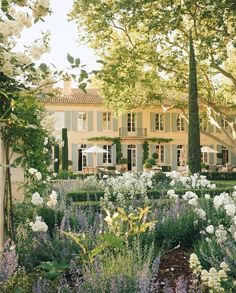 a large white house surrounded by trees and flowers