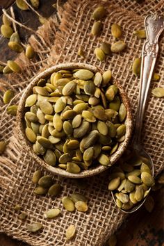 a bowl filled with seeds next to a spoon on top of a burlock