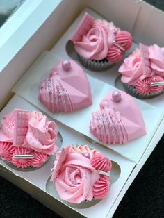 four cupcakes in a box with pink frosting