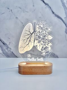 a light up lungs with flowers on the front and back side, sitting on a wooden base