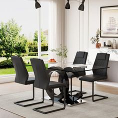 a dining room table with four chairs and a rug on the floor in front of it