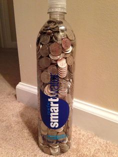 a bottle filled with lots of coins sitting on top of a carpet next to a wall