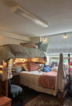 a bunk bed sitting next to a window in a room with lots of pillows on top of it