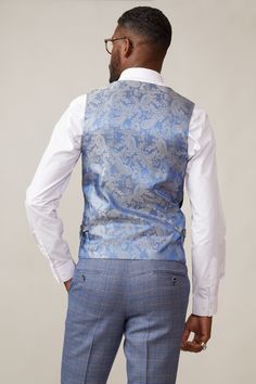 A formalwear staple, this Kelvin waistcoat epitomises versatility. In a classic navy, it is made for mix-and-match looks and breaks up patterns beautifully with its subtle textured fabric. The bespoke MD print lining adds elegance and with adjuster buckles to the each side you'll have the ability to create a perfectly contoured shape. Also available in a double-breasted option. Model wears size 38R. Features Slim fit Single-breasted 5 button fastening Complimentary pocket square Buckle adjuster Elegant Nehru Jacket For Business, Blue Sleeveless Suits For Formal Occasions, Elegant Sleeveless Blue Suits, Fitted Nehru Jacket For Business, Classic Sleeveless Nehru Jacket For Formal Occasions, Elegant Business Suit With Vest, Blue Sleeveless Formal Suits, Elegant Suits With Vest And Notch Lapel, Elegant Formal Vest In Suiting Fabric