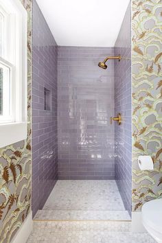 a white toilet sitting next to a shower in a bathroom on top of a tiled floor