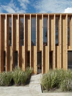 a wooden building with lots of windows and plants in front of the entrance to it