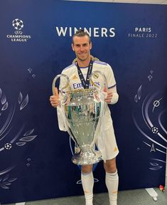 a man holding up a trophy in front of a blue wall with the words winners written on it