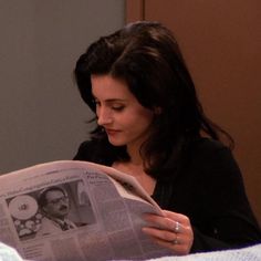 a woman reading a newspaper while laying in bed