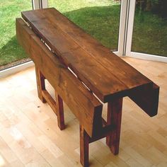 a wooden bench sitting on top of a hard wood floor next to a sliding glass door