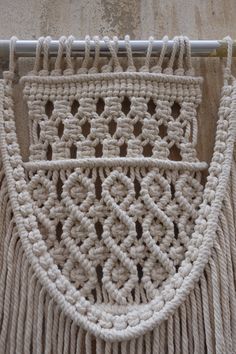 a crocheted curtain hanging on the side of a wall next to a metal pole