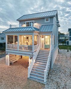 a beach house with stairs leading to the second floor and covered porchs on both sides