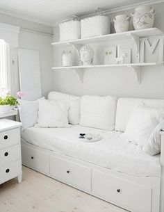 a white couch sitting next to a shelf filled with vases