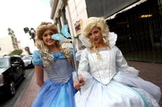 two women dressed up as princesses posing for the camera in front of a building