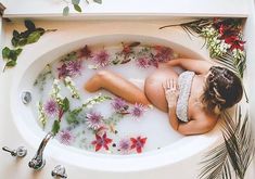 a woman laying in a bathtub filled with flowers