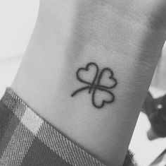 a black and white photo of a clover tattoo on someone's left wrist,