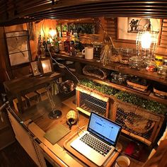 an open laptop computer sitting on top of a wooden desk next to a shelf filled with bottles