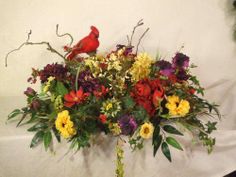 a vase filled with flowers and a cardinal sitting on top of the planter next to it