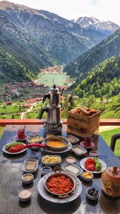 a table topped with lots of food on top of a wooden table next to mountains