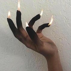 someone is holding out their hand with two fingers that are shaped to look like flames