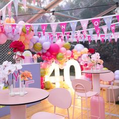 tables and chairs are set up for a birthday party with balloons, streamers and flowers