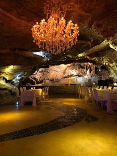 a dining room with chandelier and tables in the middle of an underground cave