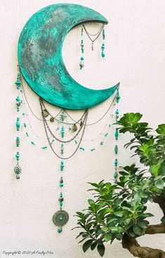 a green moon hanging on the side of a wall next to a potted plant