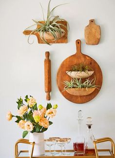 a table topped with flowers and plants next to wooden cutting board mounted on the wall