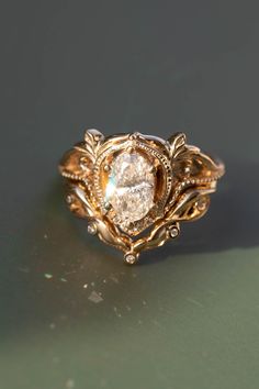 a close up of a gold ring with a diamond in the center and leaves around it