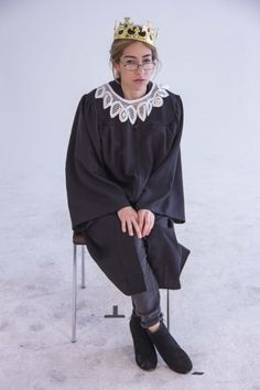 a woman sitting on top of a chair wearing a crown