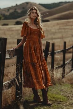 a woman in an orange dress leaning against a fence