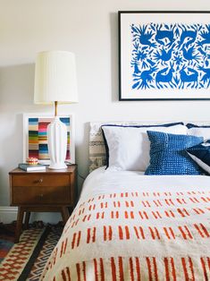 a bedroom with a bed, nightstand and pictures on the wall above it is decorated in blue and red