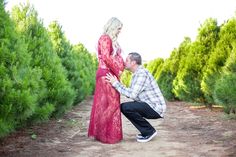 a man kneeling down next to a woman in a red dress on a dirt road