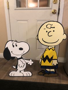 a cardboard charlie brown and snoopy standing in front of a door