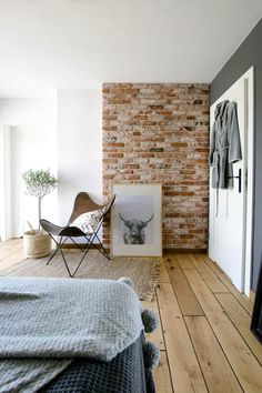 a bedroom with a brick wall and wooden floors