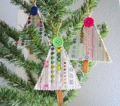 three christmas ornaments hanging from a tree with buttons and pins attached to the strings on each ornament