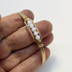 A contemporary little bracelet consisting of five strands of 14kt gold filled wire with a center design featuring five 4mm smooth glowing opalite beads and accented with two smaller 14kt gold filled beads. This sweet bracelet is stylish and simple, and it's stackable with most of my other wirewrapped bracelet styles! The opalite shifts from white to blue to lavender overtones, depending on what you wear it with, making it the perfect accessory for every outfit! The sturdy built-in hook and eye c Minimalist Gold Beaded Bracelets Hand Wrapped, Dainty Adjustable Wire Wrapped Beaded Bracelets, Gold Wire Wrapped Wrap Bracelet As A Gift, Adjustable Wire Wrapped White Bracelets, White Adjustable Wire Wrapped Bracelets, Adjustable White Wire Wrapped Bracelets, Dainty Adjustable Wire Wrapped Bracelets, Dainty Adjustable Wire Wrapped Bracelet, Adjustable Yellow Gold Wire Wrapped Bracelets